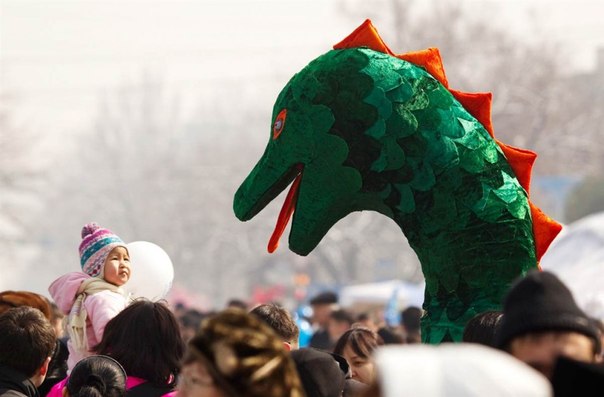 Девочка смотрит на актера в костюме дракона во время празднования Новруза в городе Алматы, Казахстан, 21 марта. Древний праздник Новруз, который отмечается по случаю весеннего равноденствия, широко распространен в Центральной Азии.