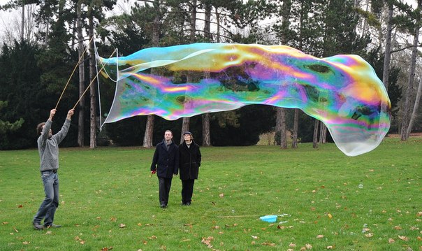 Sly Lebulleur выдувает огромный мыльный пузырь в одном из французских парков.