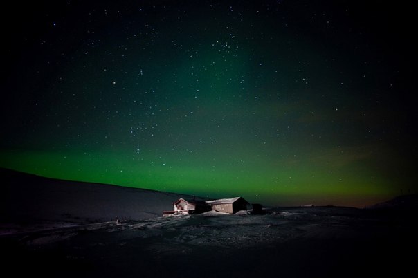 Северное сияние горит в небе над одиноким домиком в Финнмарке, Норвегия.