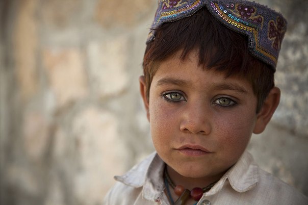 Мальчик наблюдает за афганскими национальными силами безопасности и коалиционными силами, сопровождающими окружного губернатора, в провинции Гильменд, Афганистан, 17 марта 2013.