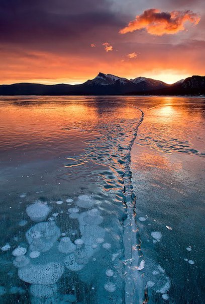 Озеро Абрахам, расположенное у подножия Скалистых гор в Канаде, стало излюбленным местом у фотографов. Оно славится своим необычным ледяным покровом, в котором можно увидеть множество замороженных воздушных пузырей. Поднимаясь со дна озера, пузырьки метана останавливаются у замерзшей поверхности, а лед с течением времени наступает в низ, захватывая их и останавливая новые пузырьки на другой глубине. В результате получаются великолепные и уникальные узоры.
