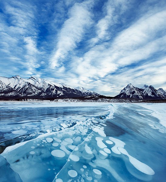 Озеро Абрахам, расположенное у подножия Скалистых гор в Канаде, стало излюбленным местом у фотографов. Оно славится своим необычным ледяным покровом, в котором можно увидеть множество замороженных воздушных пузырей. Поднимаясь со дна озера, пузырьки метана останавливаются у замерзшей поверхности, а лед с течением времени наступает в низ, захватывая их и останавливая новые пузырьки на другой глубине. В результате получаются великолепные и уникальные узоры.