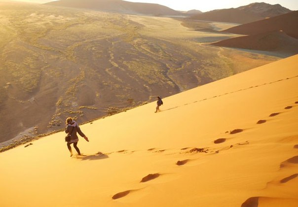 Пара спускается вниз с «Дюны 45» на восходе солнца в пустыне Намиб, Намибия