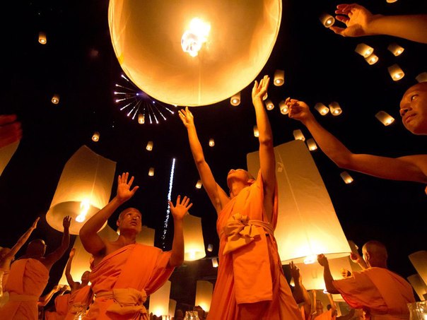 Монахи запускаю в небо фонарики у стен храма Song Pee Nong, Таиланд.