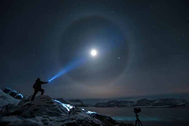 Вокруг Луны виден ореол в Квэфьорд, Тромсе, Норвегия, 19 февраля 2013 года. Такие ореолы возникают, когда лунный свет преломляется через кристаллы льда в атмосфере.