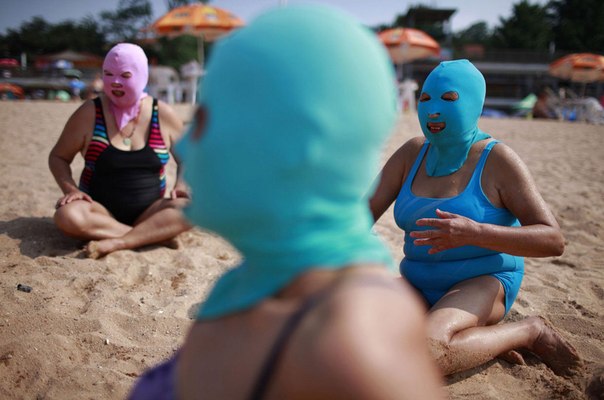 Женщины, одетые в нейлоновые маски, отдыхают на пляже в городе Циндао, провинции Шаньдун. Этот предмет одежды был изобретен семь лет назад как защита от прямых солнечных лучей. Маски поступили в массовое производство и продаются в местных магазинах вместе с купальниками. Специальный аксессуар для пребывании даже на палящем солнце помогает китаянкам сохранять упругость и молодость кожи лица, а также уберегать ее от воздействия вредных солнечных лучей во время пребывания на пляже и бороться с морщинами.