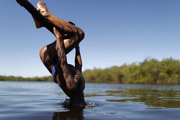 Мальчик из племени явалапити ныряет головой в реку Шингу, Бразилия.