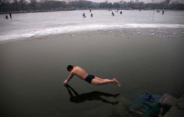 Мужчина ныряет в ледяную воду озера Хоухай в центре Пекина, Китай