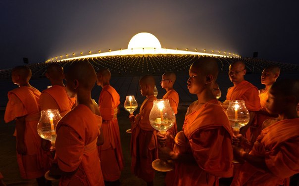 Буддийские монахи шествуют со свечами вокруг пагоды во время празднования Макха Бучи возле дхаммакайского храма в провинции Патхумтхани, Таиланд.