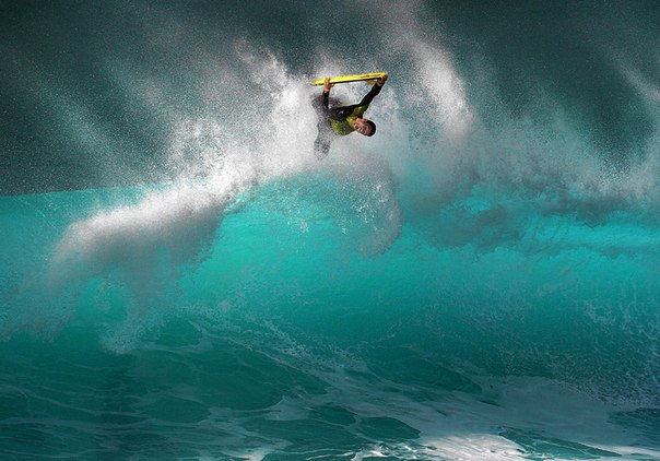 Буги-сёрфер скользит по волне на пляже Банзай-Пайплайн на северном побережье острова Оаху, Гавайские острова