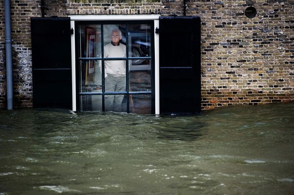 Мужчина стоит в своем доме в окружении воды в Дордрехте, Нидерланды, 5 января 2012. Штормовые ветры достигали 110 километров в час, при этом проливные дожди ударили по голландскому побережью.