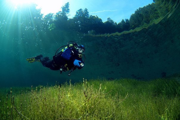 Водолаз плавает в кристально чистом озере Sameranger в Тироле, Австрия. Фотография была сделана на глубине 3 метров.