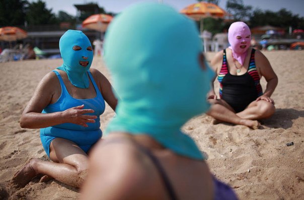 Китаянки на пляже защищают свои лица от ультрафиолета с помощью специальных нейлоновых масок. Они продаются во всех местных магазинчиках