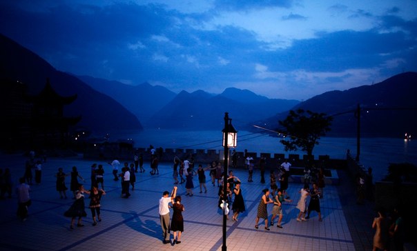 Люди танцуют на набережной реки Янцзы в Бадонге, Китай. 