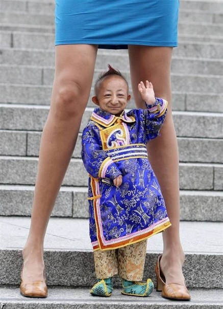 Хе Пингпинг из Монголии – самый маленький человек в мире (его рост 74,61 см) – стоит между ног Светланы Панкратовой – женщины с самыми длинными ногами.