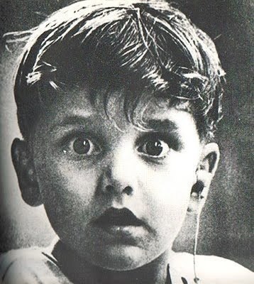 На фотографии лицо мальчика, который впервые в своей жизни услышал звук. Доктор только что установил ему слуховой аппарат в левое ухо.