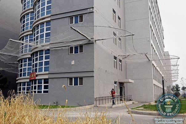 Здание фабрики Foxconn, окруженное сеткой для того, чтобы рабочие не пытались покончить с жизнью, прыгнув с крыши. Городской округ Ланфан, провинция Хэбэй, Китай.