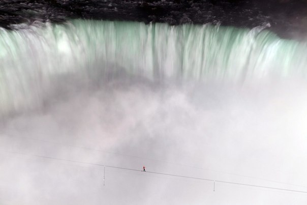 Канатоходец Ник Валленда идет по канату, натянутому над Ниагарским водопадом между США и Канадой...
