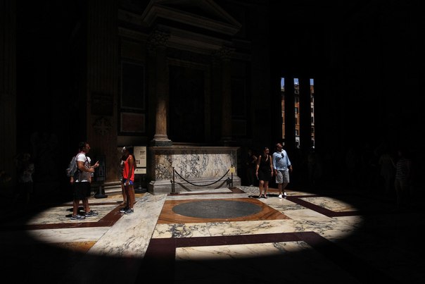 Туристы стоят в лучах света, который проникает через отверстие в куполе Пантеона, в Риме, 11 июля 2013 года.
