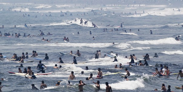 Люди занимаются сёрфингом на пляже в городе Фудзисава к западу от Токио, 15 июля 2013 года.