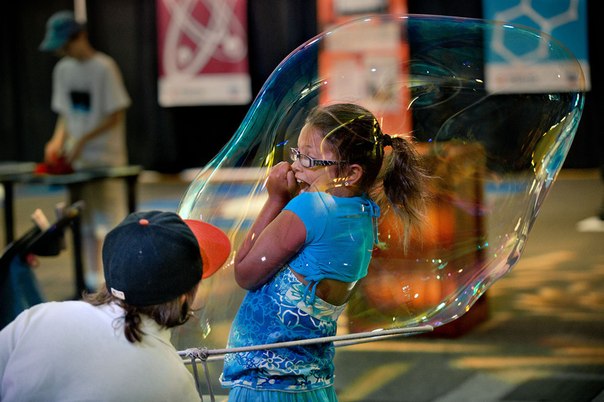 Девятилетний мальчик выдувает огромный мыльный пузырь на свою восьмилетнюю сестру на Государственной ярмарке штата Калифорния в Сакраменто, 12 июля 2013 года.