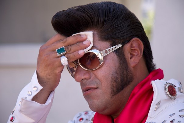 Актёр Кристиан Моралес, изображающий Элвиса Пресли, утирает пот со лба на бульваре Лас-Вегас-Стрип, где он позирует для фото с туристами, штат Невада, 27 июня 2013 года. Несмотря на сильную жару, Моралес работает в дневные часы. «Лучше страдать от жары, чем отбиваться от пьяных вечером», – говорит он.