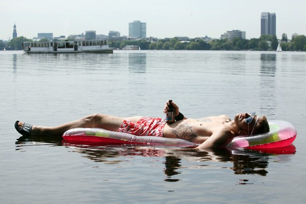 Молодой человек плавает на надувном матрасе по озеру Альстер в Гамбурге, Германия, 18 июня 2013 года.