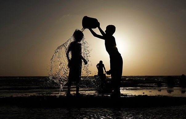 Мальчик купает своего брата на пляже в Дейр эль-Балах, сектор Газа, 27 июня 2013 года. 