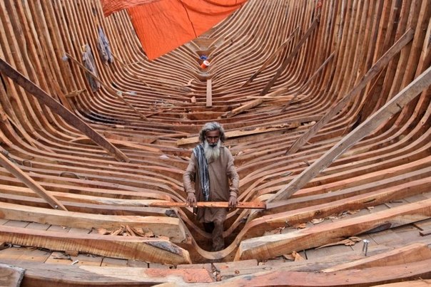 Плотник строит рыболовецкое судно в порту Карачи, Пакистан.