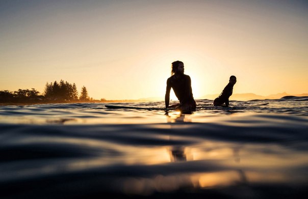 Люди вышли поплавать на досках для сёрфинга на рассвете в городе Байрон-Бей, Австралия.