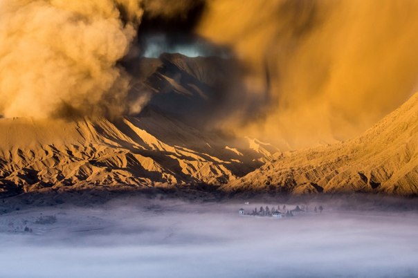 У подножия активного вулкана Бромо на острове Ява находится индуистский храм Пура Лухур Потен, который часто утопает в тумане с приходом сумерек. В этот день вулкан Бромо выбросил густое облако пыли. 