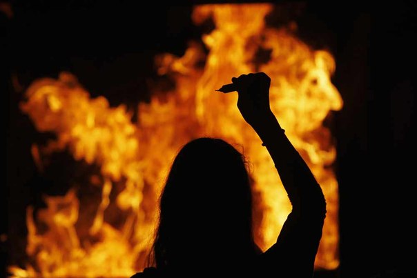 Иудейка бросает свечу в огонь во время церемонии в городе Нетивот, Израиль.