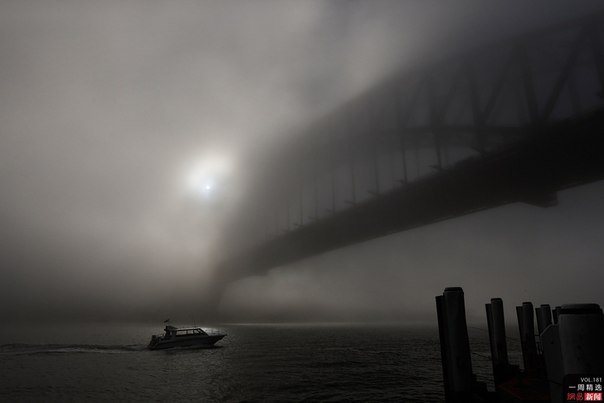 Катер проплывает под окутанным туманом мостом Харбор-Бридж в Сиднее, Австралия. 