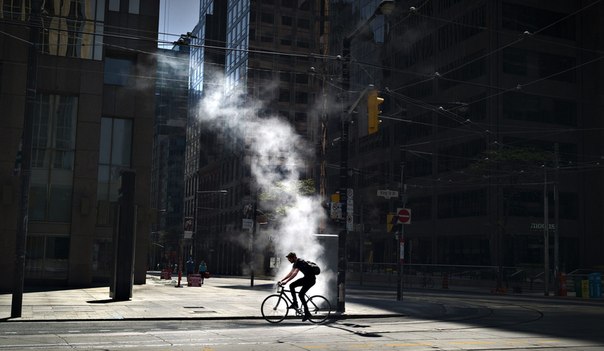 Велосипедист едет по пустой улице в деловом районе в Торонто, Канада.
