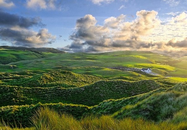 Утреннее солнце касается холмов и песчаных дюн в Ирландии. 