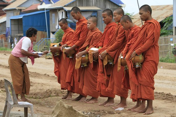 Камбоджийская крестьянка (слева) предлагает еду буддийским монахам, которые собирают подаяния в деревне Barach в 6 километрах к северо-востоку от Пномпеня, Камбоджа.