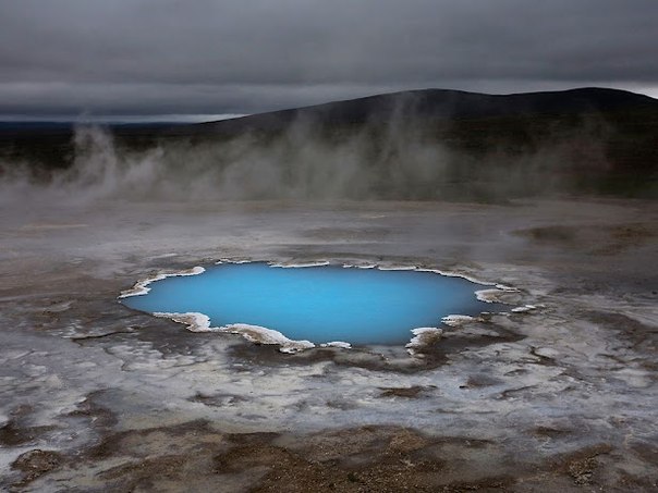 Этот ярко-голубой горячий источник кажется волшебным среди серого неба и сурового исландского ландшафта. 