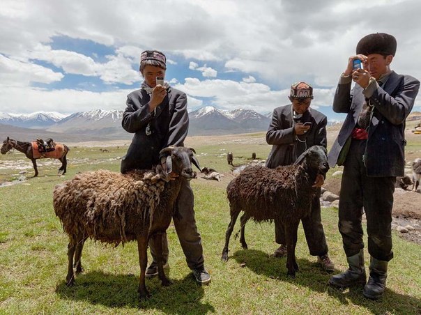 Киргизские пастухи стоят на пастбище с мобильными телефонами, которые они заряжают с помощью солнечных батарей. Хотя телефоны бесполезны здесь для общения, ими пользуются, чтобы слушать музыку и делать фотографии.