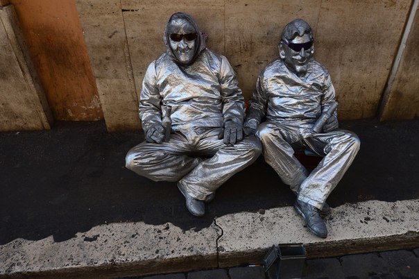 Уличные артисты сидят на тротуаре недалеко от площади Навона в Риме, Италия.