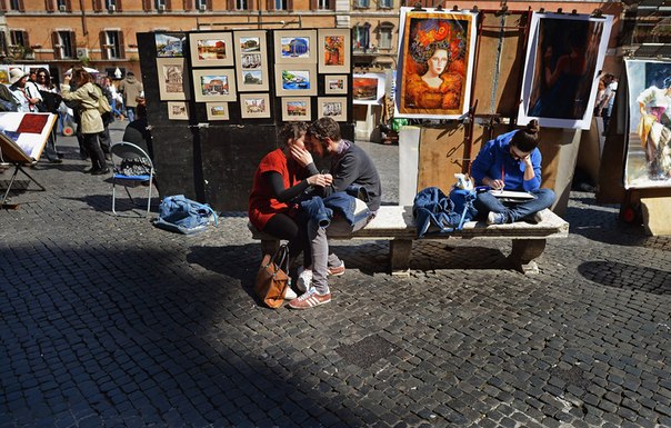 Влюблённые сидят на лавке на площади Навона в Риме, Италия.