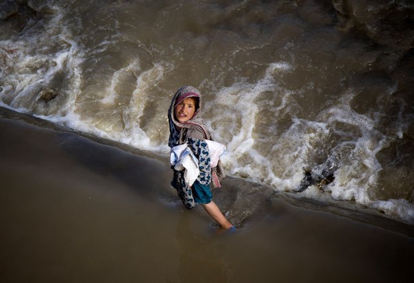 Девочка идёт по бурлящему ручью на окраине Кабула, Афганистан, 15 мая 2013 года.