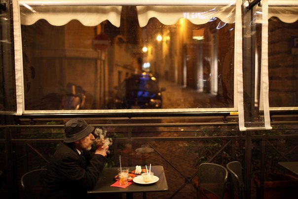 Мужчина курит в кафе в Риме, Италия.