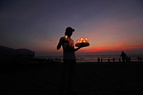 Индиец несёт свечи на столики в ресторане на берегу Аравийского моря на Гоа, Индия.
