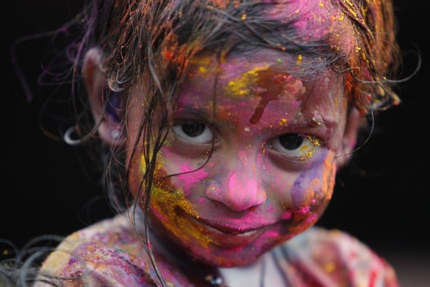 Девочка, осыпанная цветной пудрой, улыбается во время празднования Холи в Куала-Лумпуре.