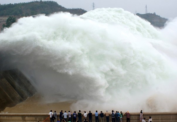 Туристы смотрят как вода сбрасывается в водохранилище на Хуанхэ, Китай. 