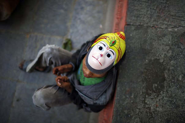 Ребёнок в маске индусского обезьяноподобного бога Ханумана сидит на улице в Катманду, Непал, 2 ноября.