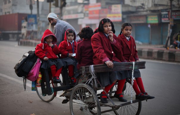 Индийские девочки едут на велорикше, относительно опасном, но дешевом виде транспорта, в школу на окраине Нью-Дели, Индия, 23 ноября.