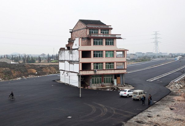 Дом стоит посреди новой дороги в городе Wenling в провинции Чжэцзян, Китай, 22 ноября. Этот дом принадлежит пожилому мужчине, который отказался подписать разрешение на снос, так как правительство предложило ему в качестве компенсации слишком маленькую сумму.