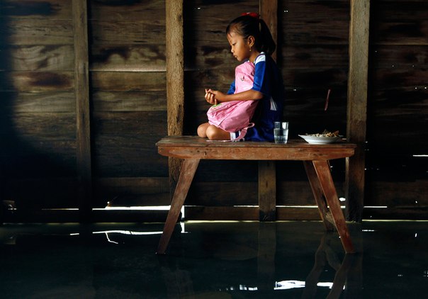 Малышка Ани молится, сидя на столе в своем затопленном доме в деревне около портового города Демак, остров Ява, Индонезия. Деревня, где проживает около 188 семей, находится примерно в одном километре от пляжа, и в течение последних нескольких лет затоплена морской водой из-за повышения уровня моря. 