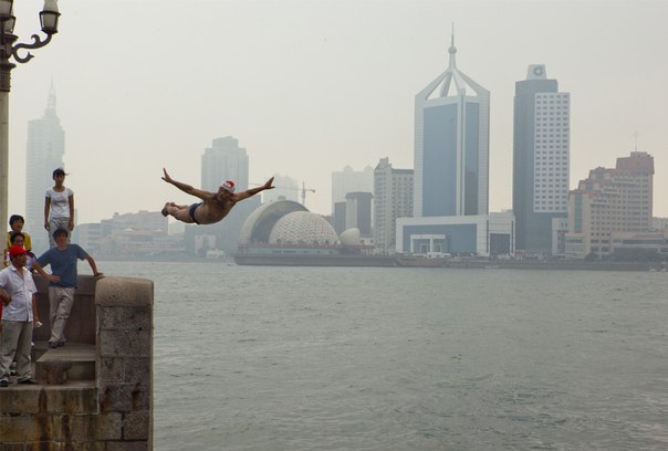 Мужчина прыгает в залив Киаучоу в Циндао, Китай. 